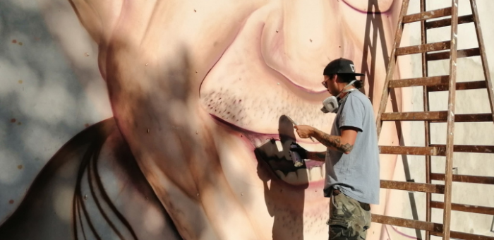 Gallino durante la elaboración del mural. Artista pintando muro con la cara de Omar Gutierrez