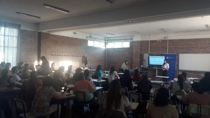 Docentes sentados y equipo de Educación Inclusiva de pie junto a una pantalla presentando actividad.