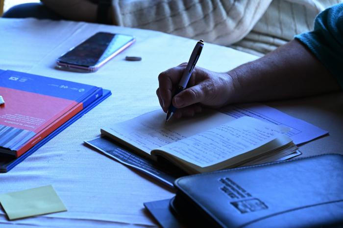 Persona escribiendo con lapicera sobre un cuaderno en blanco