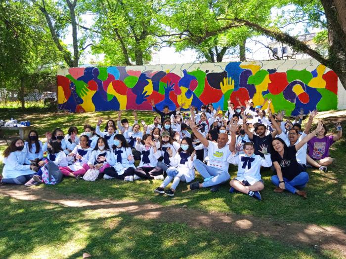 En la imagen aparece el grupo escolar junto a referentes del proyecto. Atrás el muro realizado.