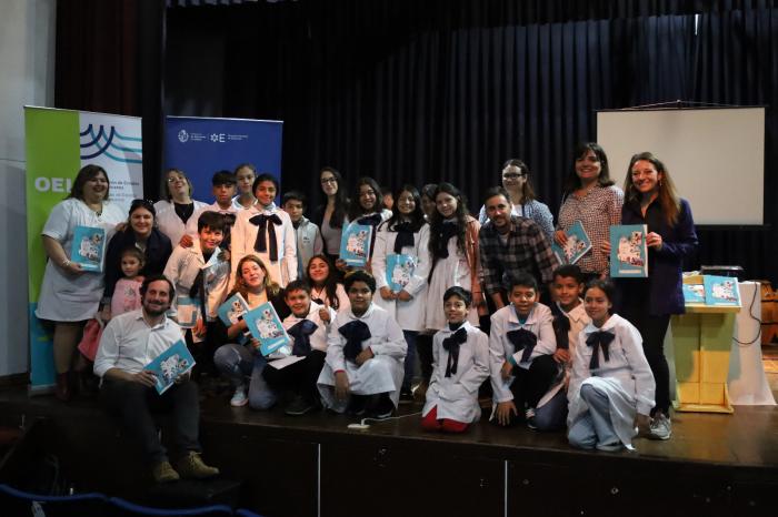 Asistentes posando para una foto junto a las autoridades en el escenario del auditorio