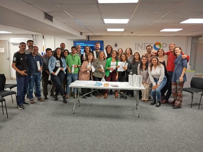 Participantes de pie posando junto a sus diplomas