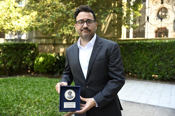 Bayona sosteniendo la Medalla Delmira Agustini.