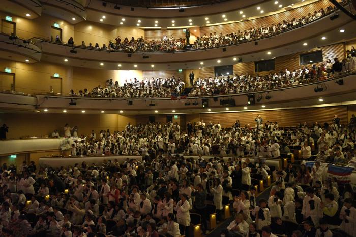 Cientos de personas sentadas en un gran auditorio