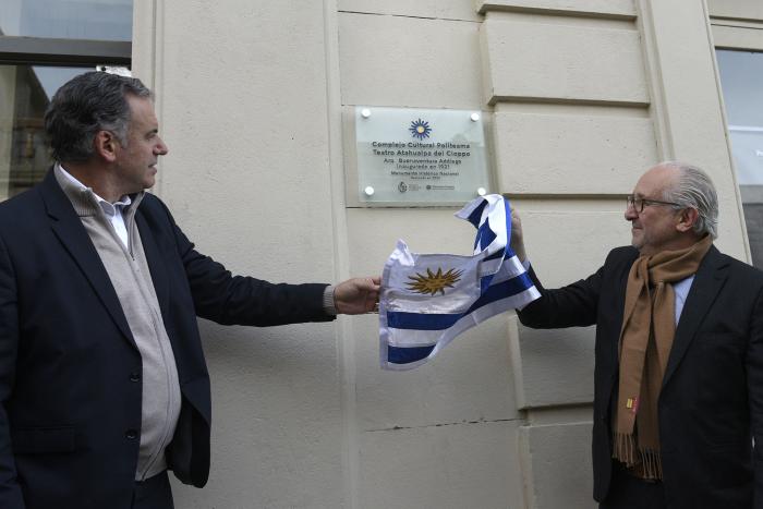 Dos personas tirando del pabellón nacional para descubrir una placa