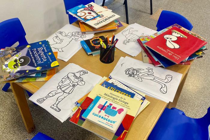 Parte del material entregado Libros y dibujos de diversos colores y formas sobre una mesa escolar para niños