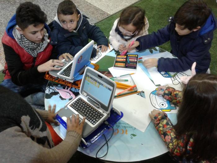 Niñas y niños en mesa con computadoras