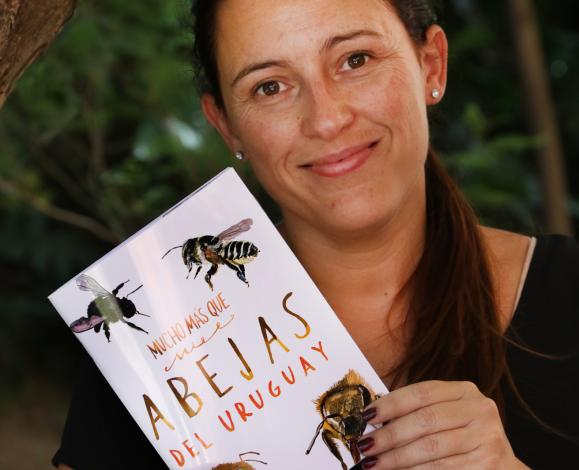 Karina Antúnez mostrando la tapa del libro."Mucho más que miel. Abejas del Uruguay"