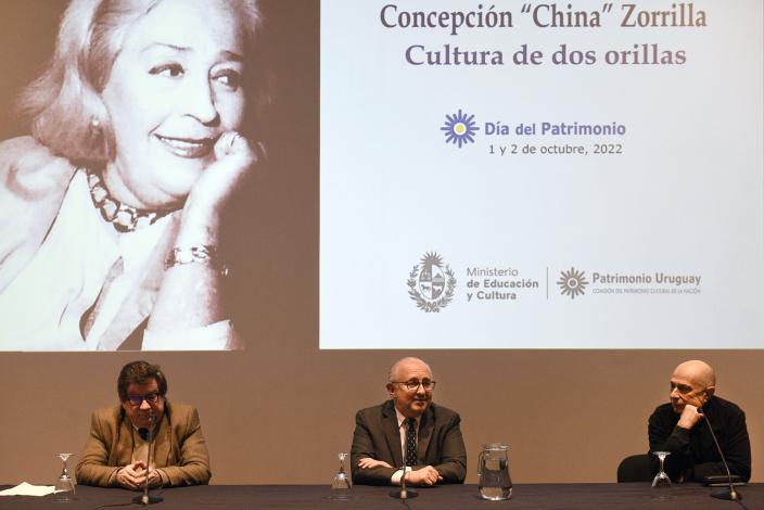 Tres hombres sentados y de fondo una imagen de China Zorrilla