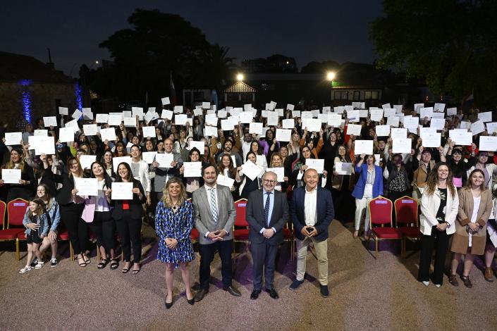 Personas con diplomas en alto, sonriendo