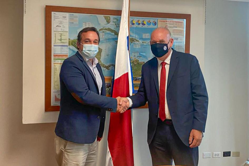 Subsecretario Verri saluda al secretario de Energía de Panamá; detrás hay una bandera de ese país