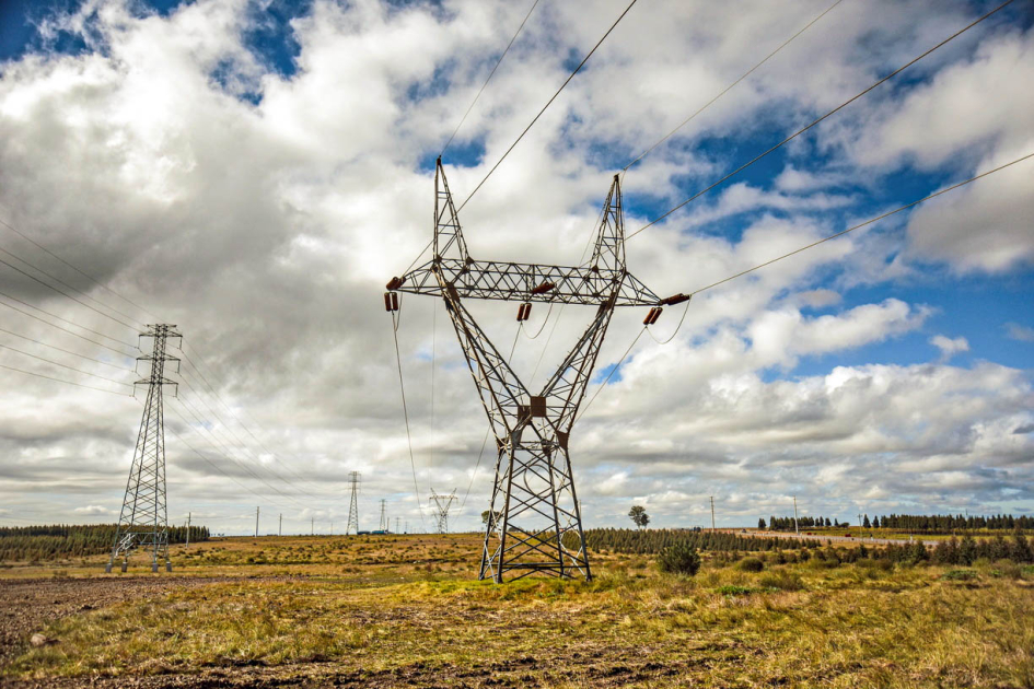 La ministra Fernanda Cardona habló sobre interconexión energética ante un auditorio regional Torre eléctrica en el campo, bajo un cielo con nubes