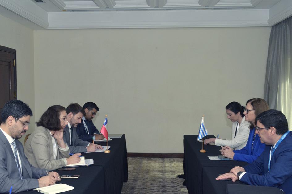 Delegaciones de Uruguay y Chile, sentadas en mesas enfrentadas