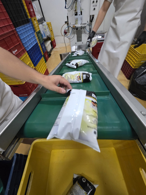 Manos de trabajadores manejan sachets de leche cocolatada dentro de la planta industrial