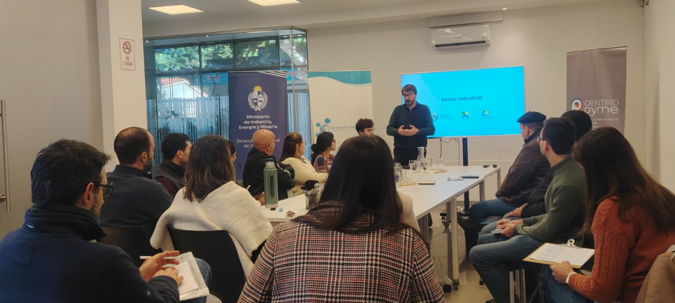 Director Míguez de pie en el taller del Fondo Industrial en Durazno; frente a él, personas sentadas
