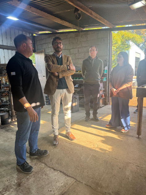 Director nacional de Industrias visitó la empresa Trailersuy Míguez y otras personas, de pie dentro de la planta