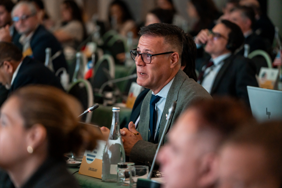 Siris habla, sentado junto a muchas otras personas