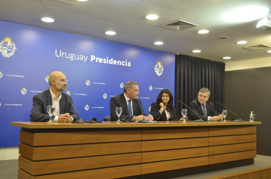 Panel de autoridades; detrás hay un banner de Presidencia