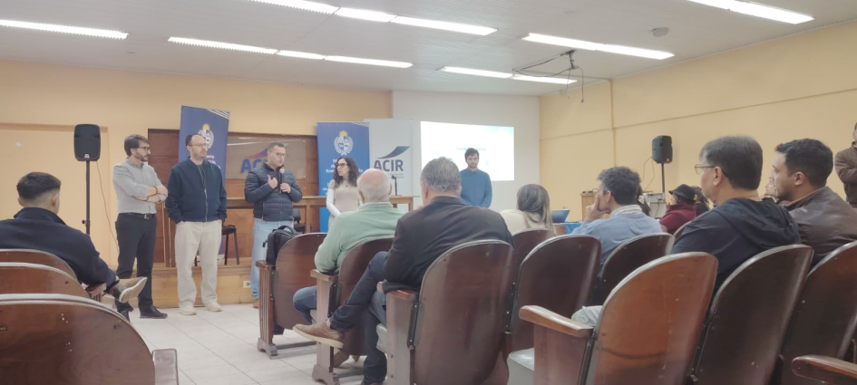 Salón con público sentado; al fondo, personas de pie