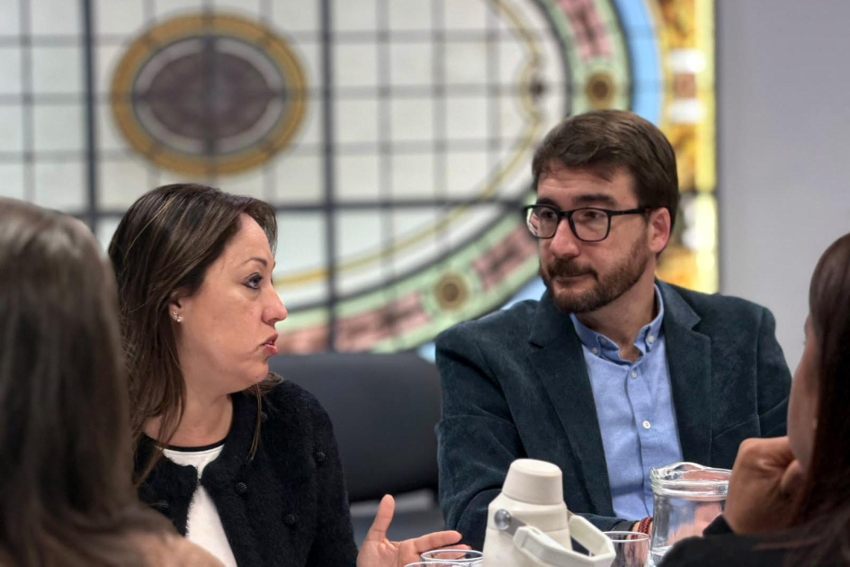 Ministra Fernanda Cardona y director Adrián Míguez Cardona habla, sentada junto a Míguez; detrás, vitral; frente a ellas, de espalda, dos mujeres