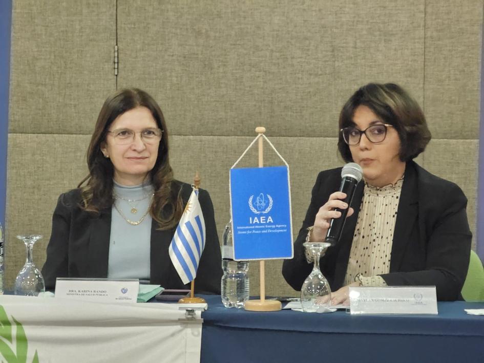 Ministra de Salud Pública, Dra. Karina Rando y Experta del OIEA, Maylen López Dos mujeres frente a una mesa. Una de ellas está hablando frente a un micrófono
