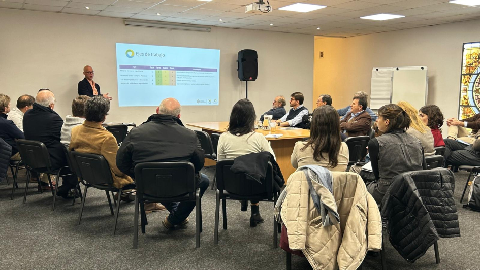 Damián Pirrocco presentó los avances del Núcleo Productivo Farmacéutico Damián Pirrocco, de pie, al lado de pantalla; participantes, sentados y sentadas