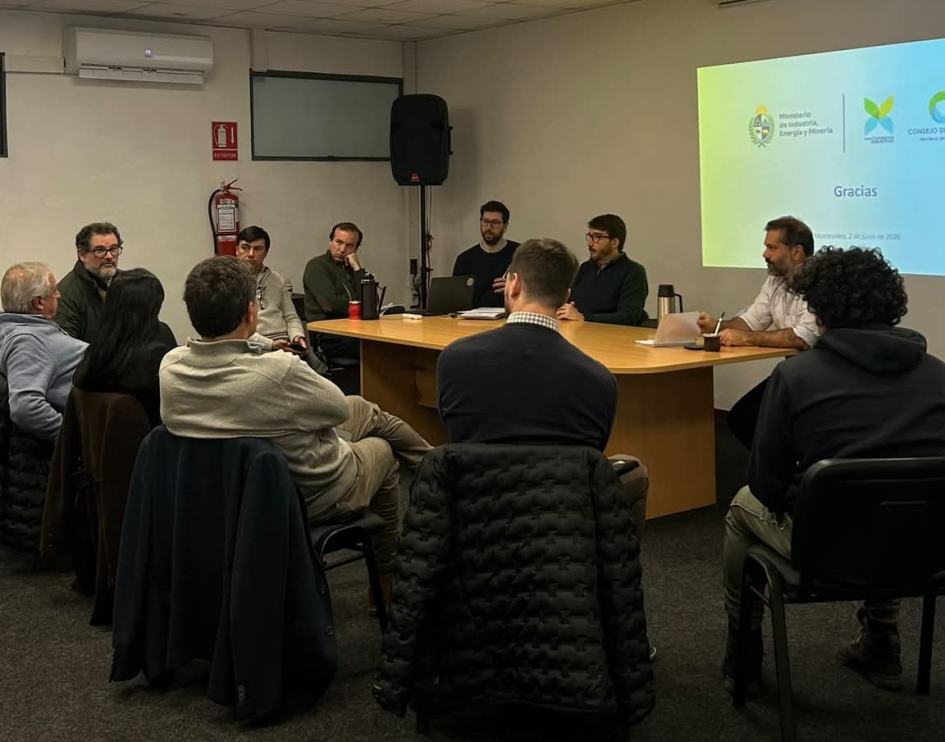 Personas sentadas al rededor de una mesa; en la pared, diapositiva