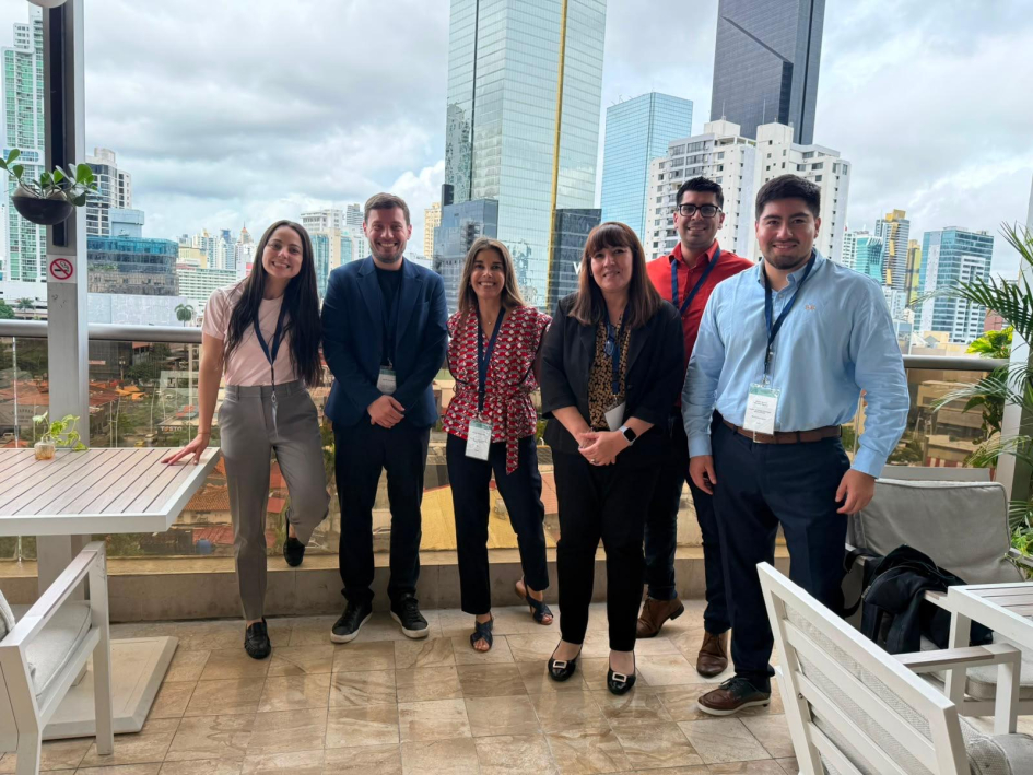Foto grupal de la delegación uruguaya Representantes de Uruguay, de pie en un espacio abierto; detrás, edificios