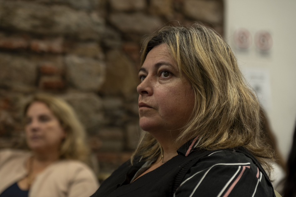 Negro, sentada; al fondo se ve otra mujer