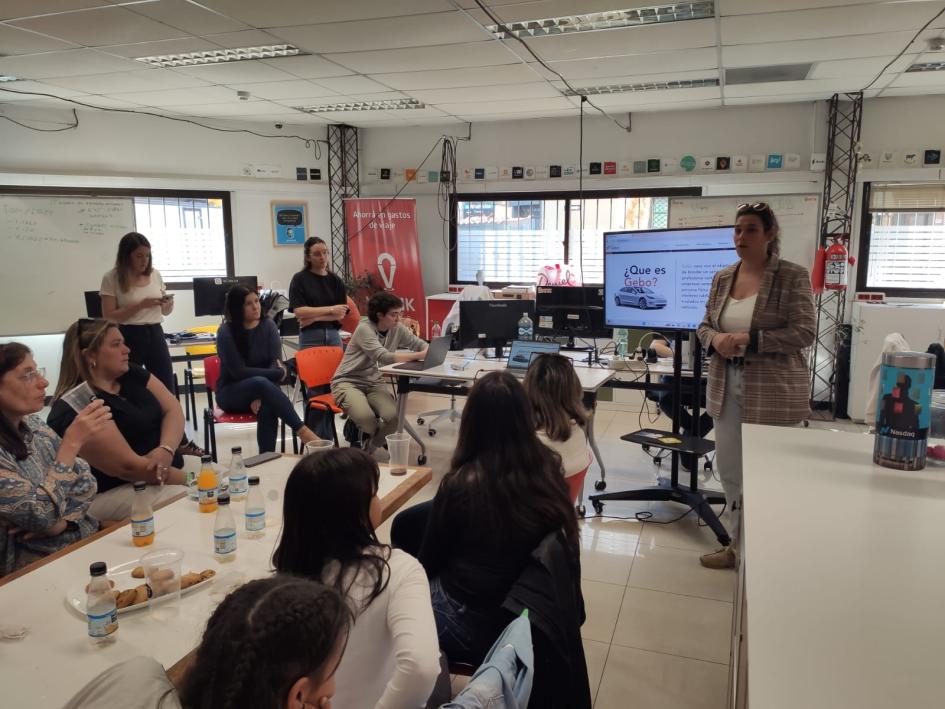 Mujer presentando a otras frente a una pantalla