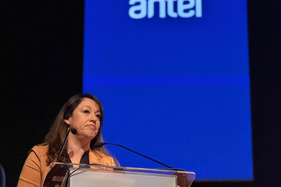 Ministra Fernanda Cardona Cardona habla desde un atril; detrás, pantalla con el logo de Antel