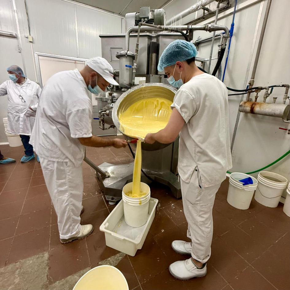 Personas con túnicas tiran producto lácteo en un recipiente