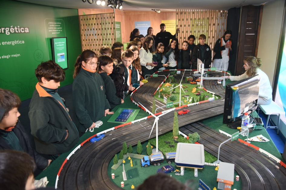 Estudiantes interactúan con maqueta en el stand del MIEM. 