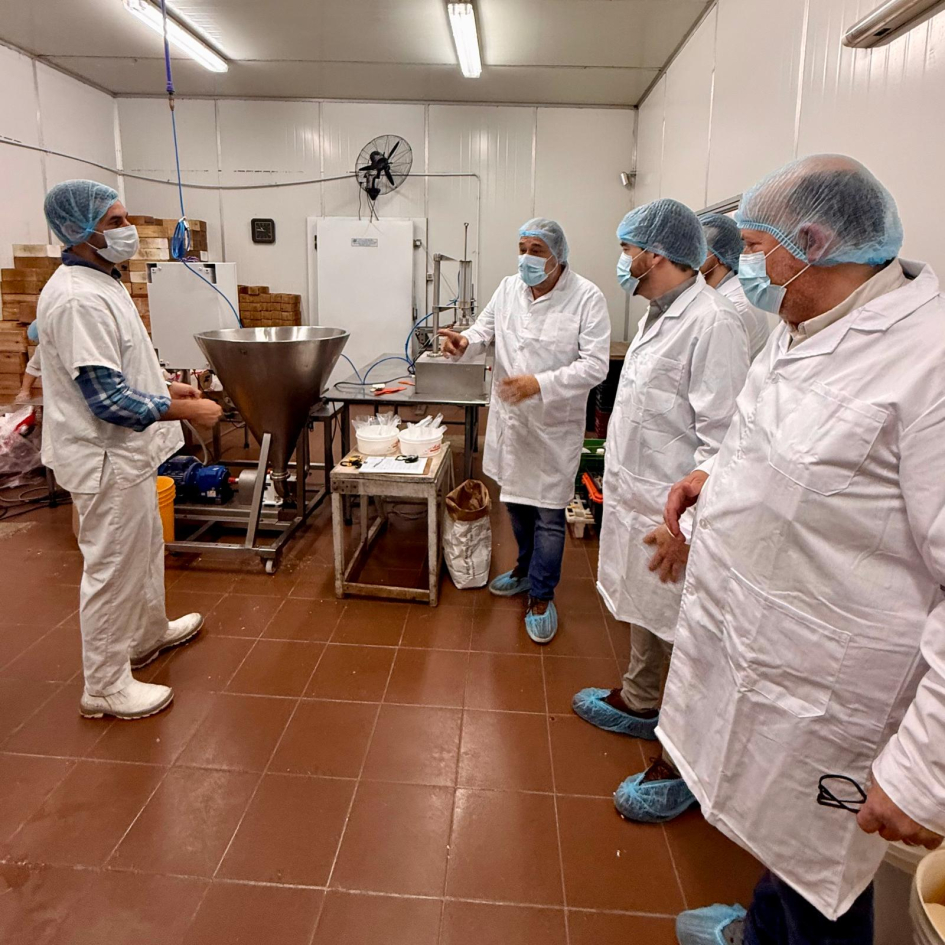 Personas visten túnicas, gorros y tapabocas en planta industrial