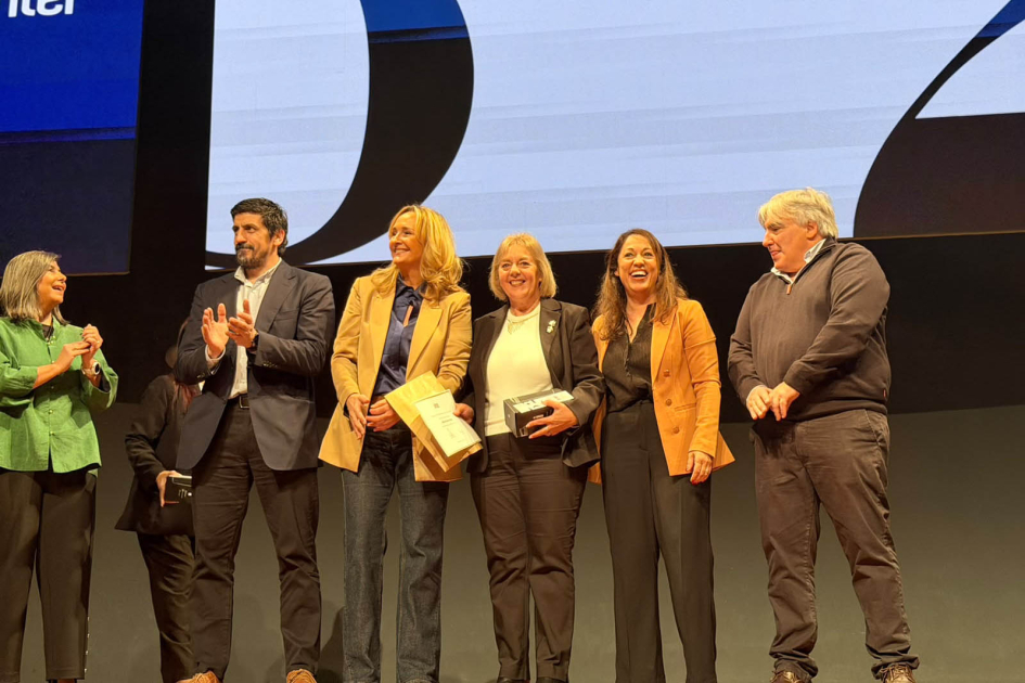 Conmemoración del 52.° aniversario de Antel Autoridades de Antel, sobre un escenario; una fuincionaria con un diploma