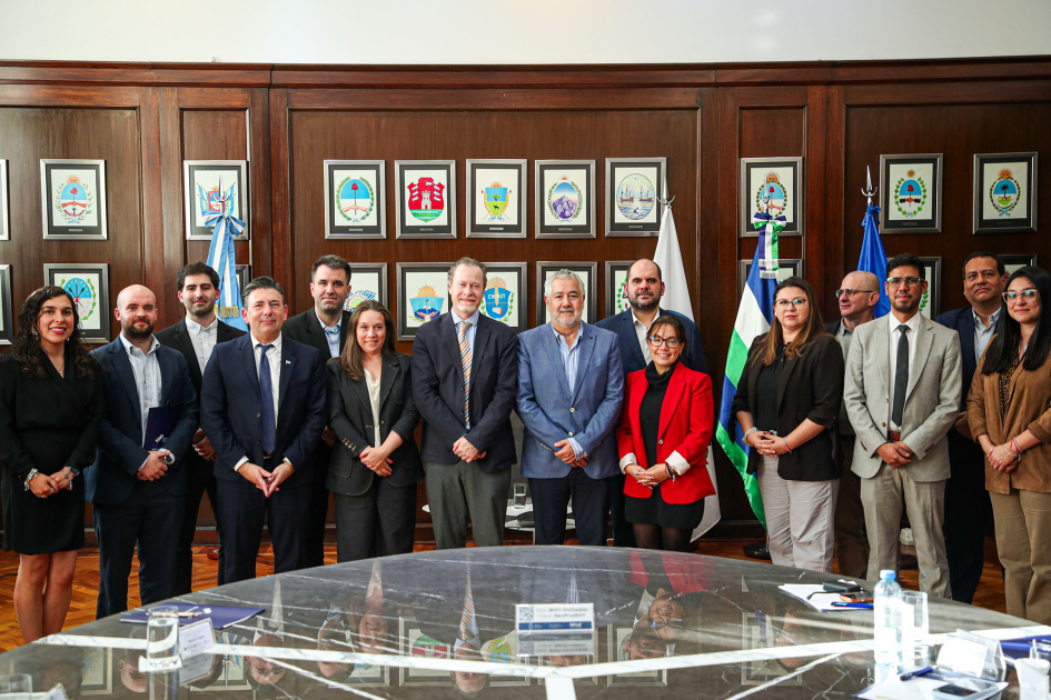 Personas de pie, detrás de una mesa; detrás, cuadros