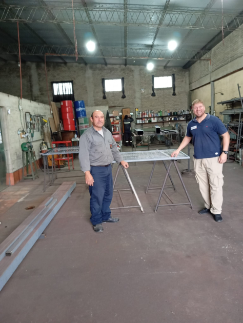 Dos hombres, de pie, dentro de un galpón
