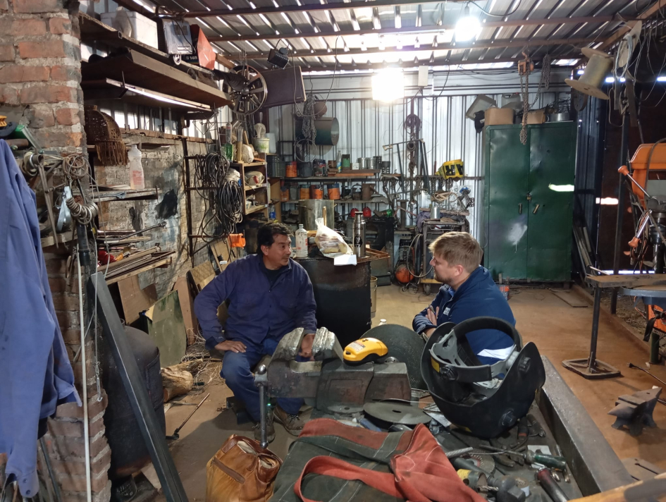 Dos hombres, vestidos de mameluco azul, en una empresa metalmecánica