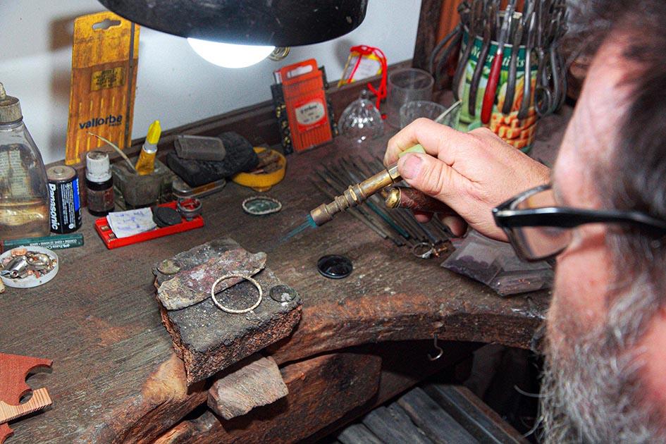 Artesano Yamandú Olivera en su taller (foto: Jorge Caggiani). Un hombre maneja herramientas sobre la mesa de su taller