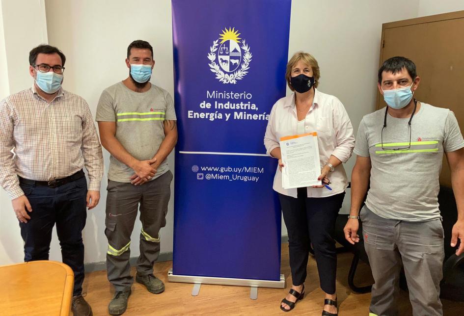 Constructores Unidos junto a autoridades del MIEM; entre ellos hay un banner de la institución