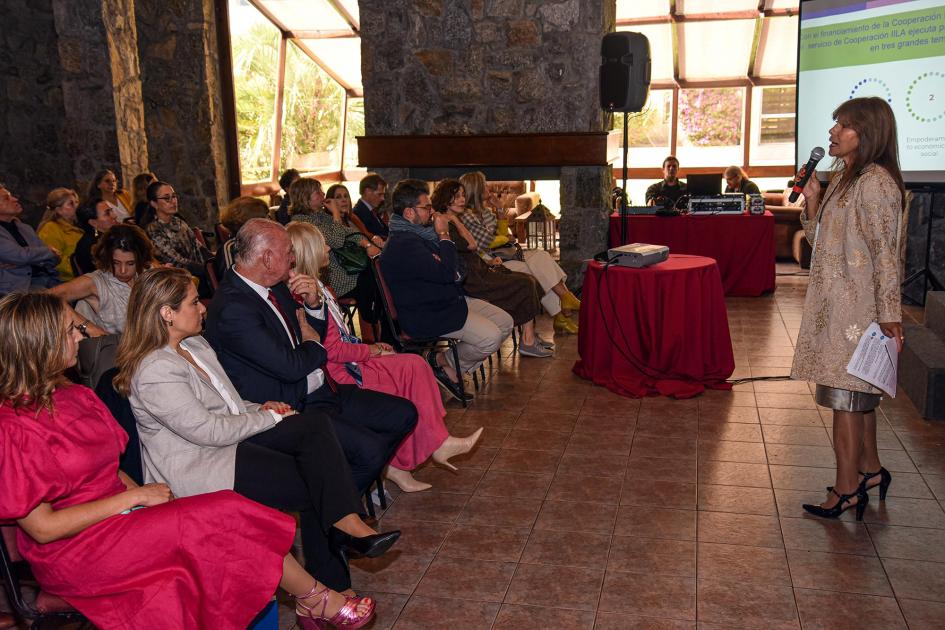 Esperanza Anziola, de IILA Anziola se dirige al público; a su lado, lejos, una pantalla