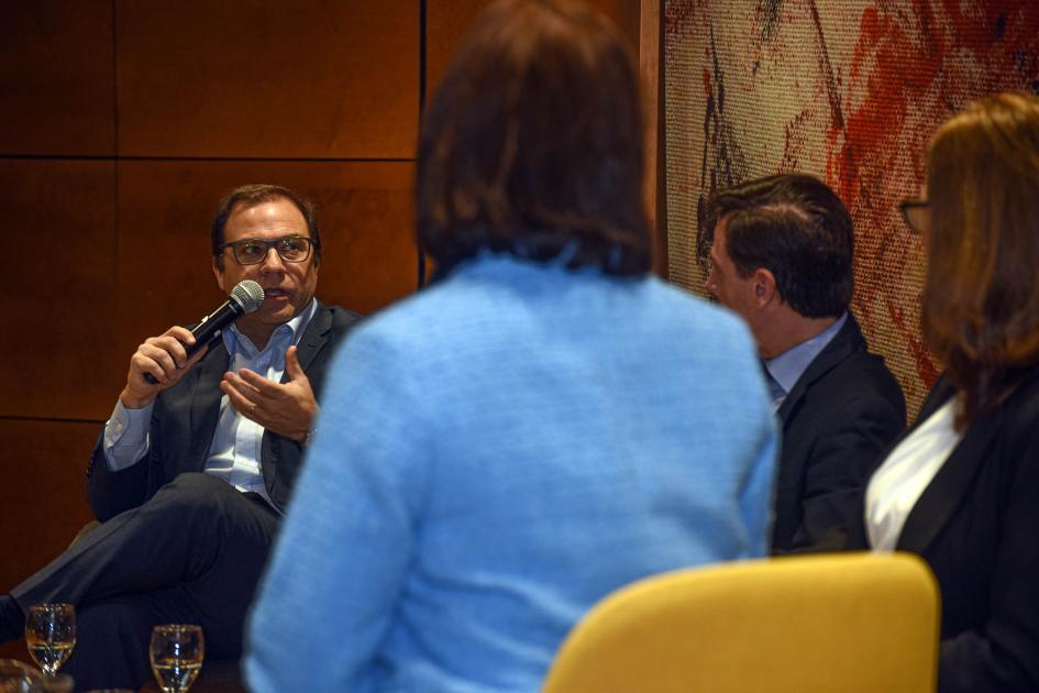 Presidente de la CUTI, Carlos Acle Acle habla con un micrófono, sentado; en primer plano, Fulton, de espada