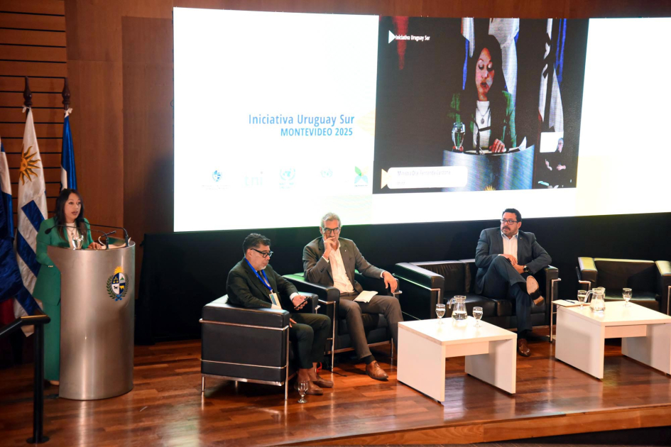 Apertura de iniciativa Uruguay Sur Escenario: Cardona habla desde un atril; tres personas, sentadas; detrás, pantalla