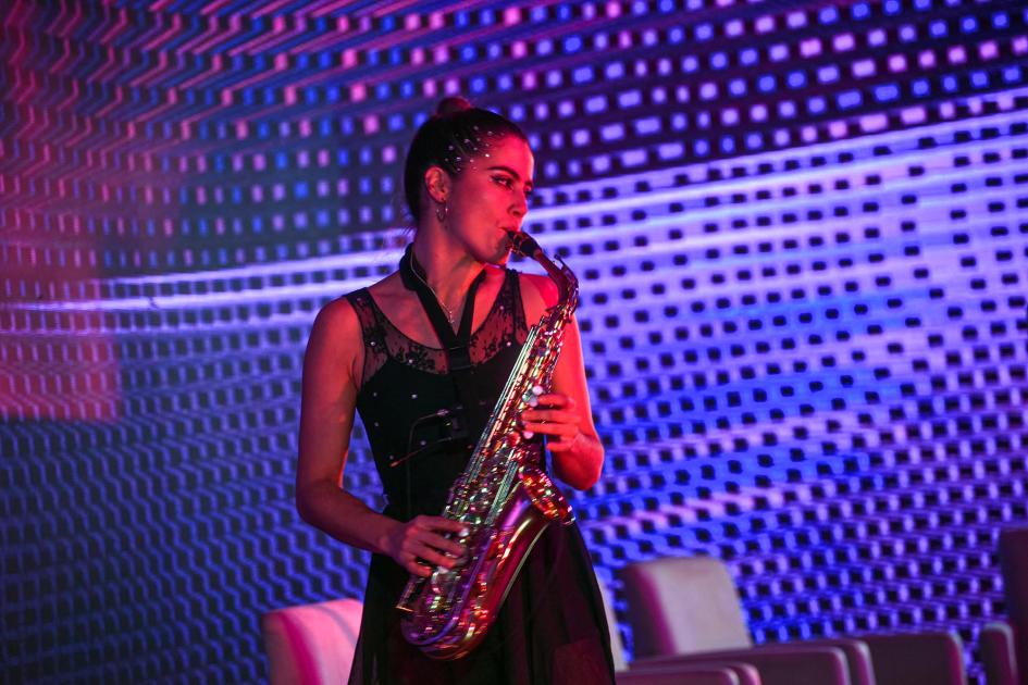 En el evento se mostró parte del trabajo en industrias creativas que realizan el laboratorio y UTEC Mujer toca el saxo; detrás, una pantalla violeta