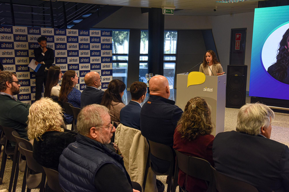 Al fondo, Cardona habla desde un atril; frente a ella, público, sentado