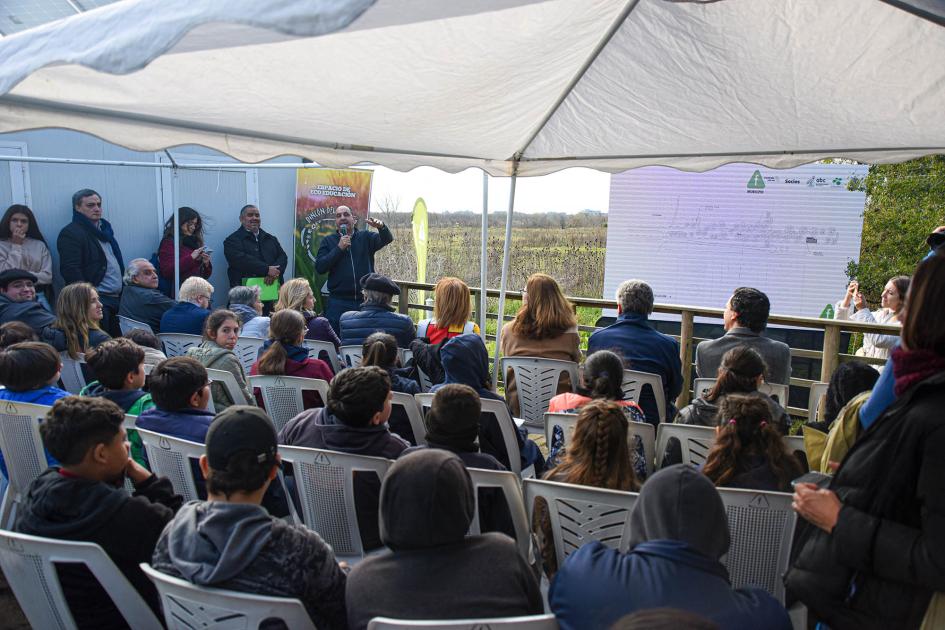 Alcalde del Municipio F, Juan Pedro López Público; al fondo habla el alcalde y hay un banner y una pantalla