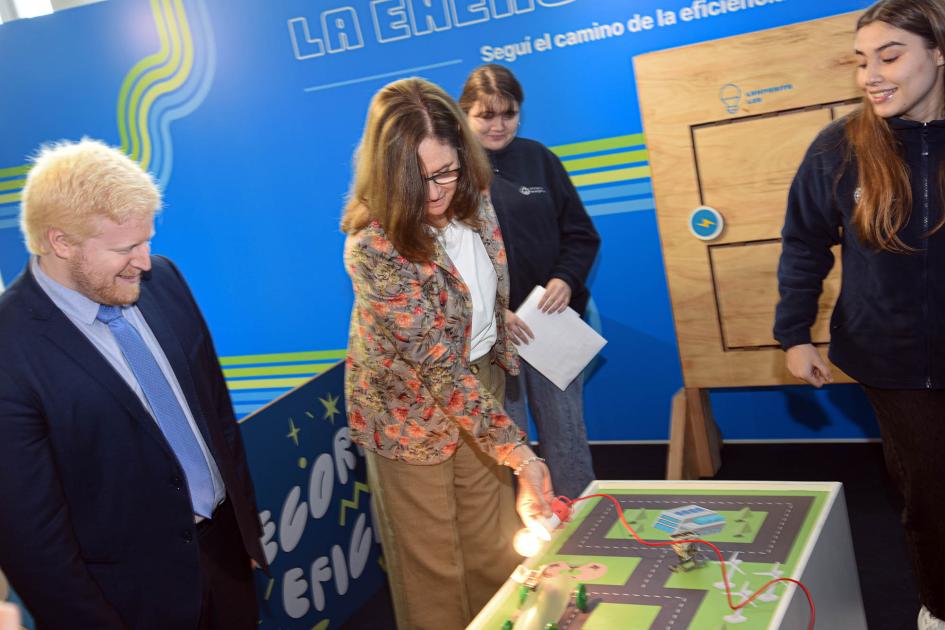 La ministra Elisa Facio y el director Christian Nieves, en los stands de Eficiencia Energética La ministra toma una lamparita sobre un circuito con un auto; a su lado, Nieves y una joven