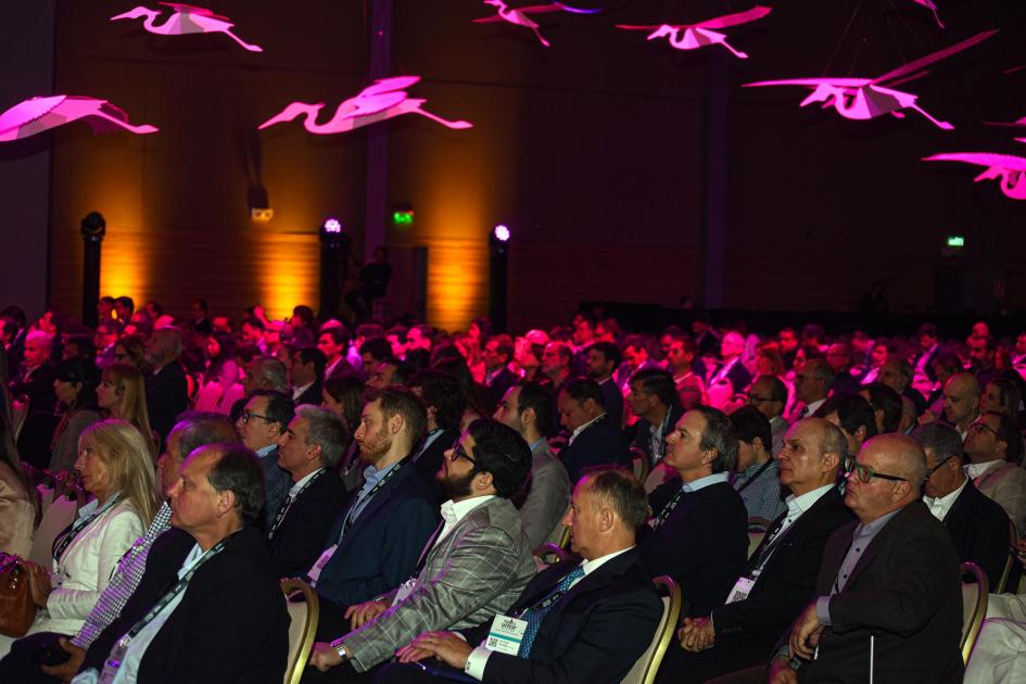 Público en una sala grande con luces rosadas