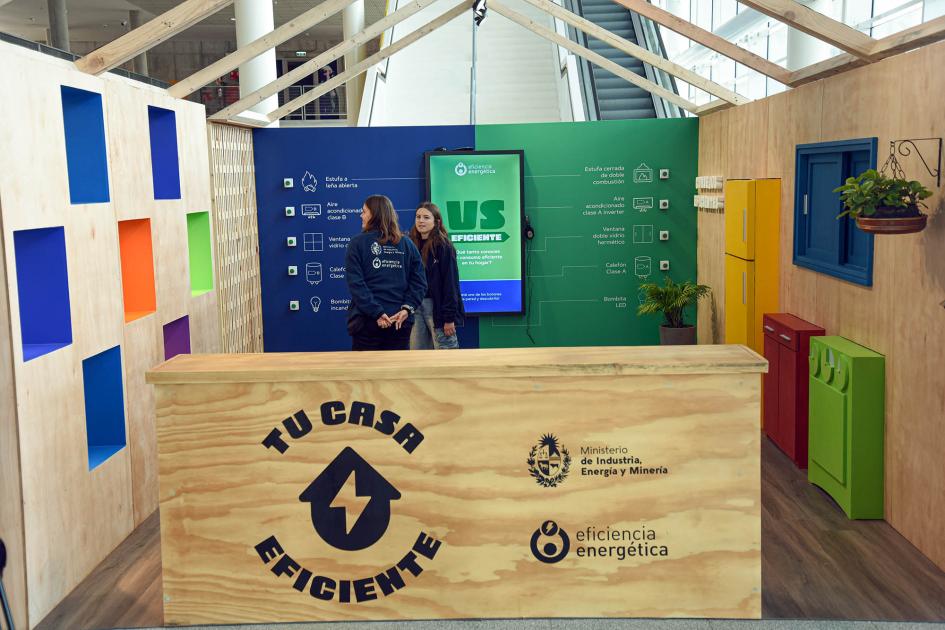 Espacio de Eficiencia Energética, en el primer piso Stand en el que predominan los colores y hay un mostrador que dice "Tu casa eficiente"