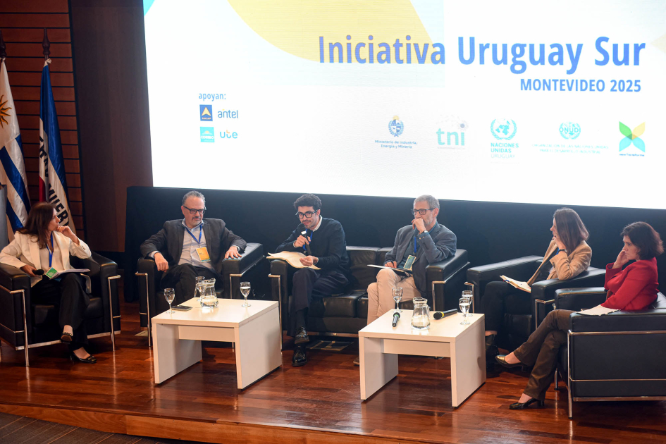 Panel 5 de la primera jornada del encuentro Moderadora y cinco panelistas, sentados; detrás, pantalla